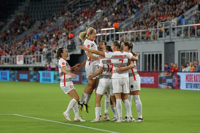 women soccer players celebrating a goal