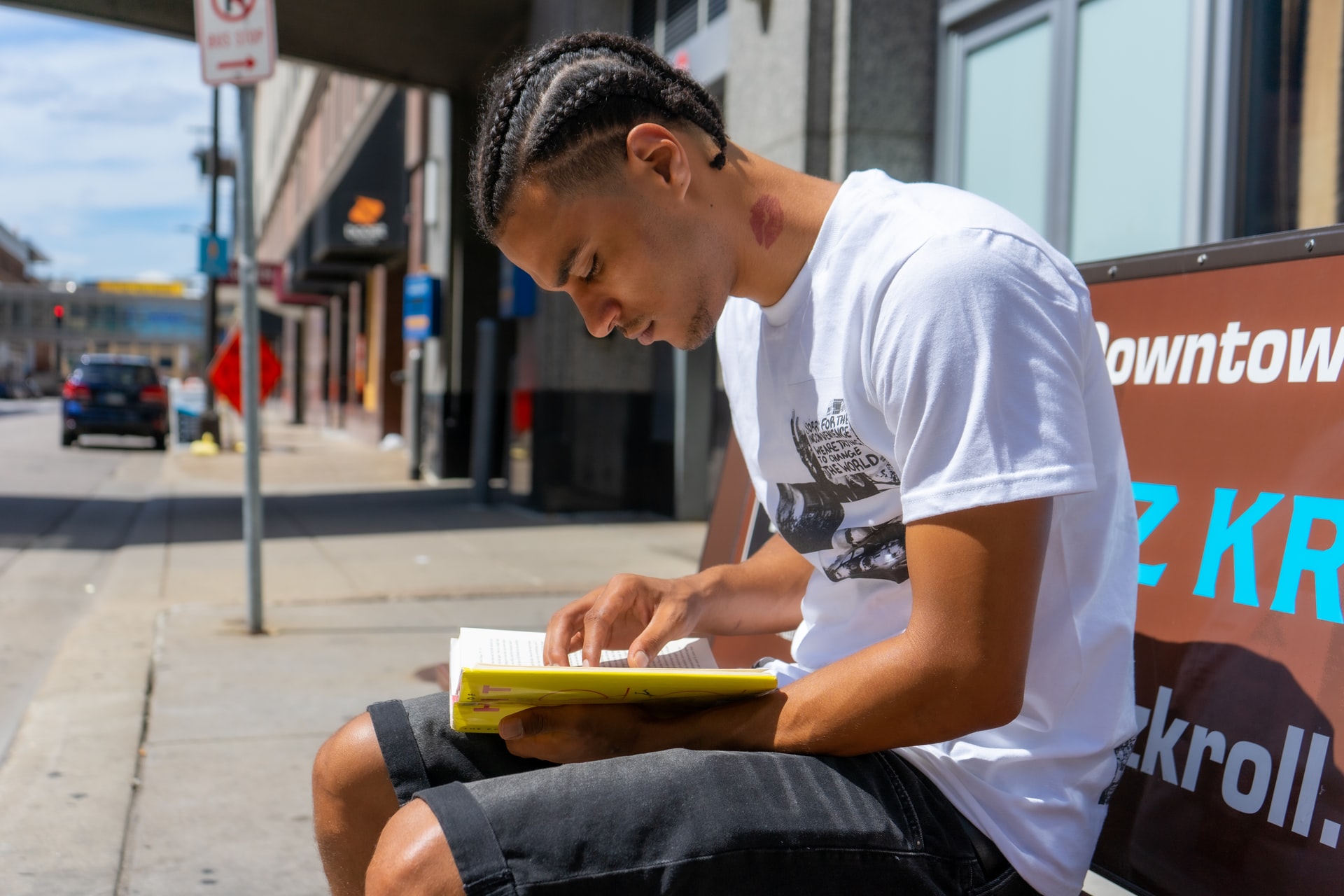 Man in a white shirt reading a book outside